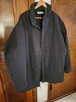 Front view of black Calvin Klein winter coat on hanger showing overall design