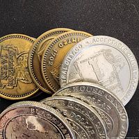 Stack of assorted brass-tone and silver-tone Colorado casino tokens