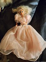 Full view of Barbie in peach gown on black surface