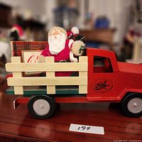 Overall view of red pickup truck with Santa, bear and gift box