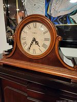 Front view of Howard Miller tambour mantel clock on wooden furniture
