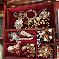 Open jewelry box showing assorted jewelry pieces in upper and lower trays