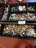 Top view of jewelry box showing upper tray compartments filled with assorted jewelry