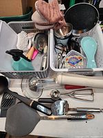 Overall view of assorted kitchen tools spread on table and in two bins