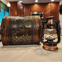 Lantern beside barrel-top chest on table