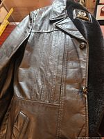 Front upper view of black leather coat on table