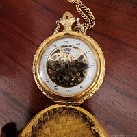 Pocket watch open showing skeleton dial and inner cover texture