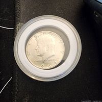 Obverse of 1964 Kennedy half dollar in capsule