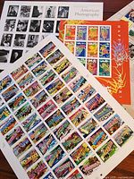 Three stamp panes spread on table showing 50-state sheet, photography sheet and partial lunar sheet