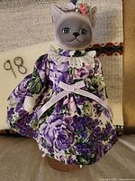 Front view of porcelain cat doll in floral dress