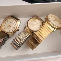 Three gold-tone watches side by side showing overall condition and bands