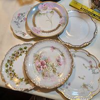 Group of six assorted floral porcelain plates overlapped