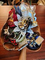 Overview of wooden leaf bowl filled with jewelry, glass pieces, belts