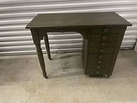 Full view of antique desk showing pedestal drawers, turned leg, casters, olive paint