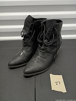 Front and side view of both black ankle boots showing lace-up design and pointed toes