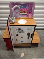Front and side view of entire play kitchen showing sink, faucet, fridge door, and side step