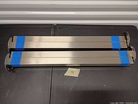 Two stacks of stainless steel rectangular table legs taped together showing length and finish