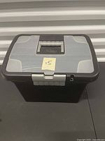 Front angled view of black and grey plastic file box showing lid, handle, and latch