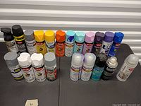 Group shot of all spray paint, primer and clear coat cans on table