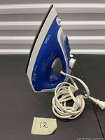 Side profile of T-fal steam iron showing body, soleplate, and coiled power cord