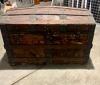 Front view of antique domed steamer chest showing iron strapping and wear