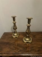 Pair of brass candlesticks standing on wood surface