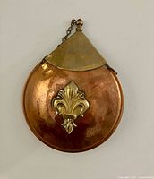 Front view showing copper body with brass fleur-de-lis and neck