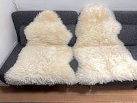 Both white sheepskin rugs displayed side-by-side on sofa