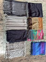 Eight folded scarves displayed on glass surface