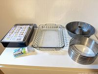 All items laid out: cookie press set box, glass baking dish, bundt pan, adjustable cake ring, pastry bags