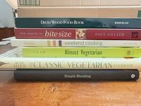 Stack of six cookbooks showing spines with titles and authors