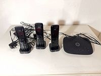 Overall lot view showing three cordless handsets on charging cradles, base station and cords