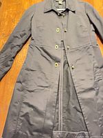 Full front view of black raincoat laid flat