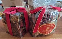 Two sealed packages of holiday potpourri side by side showing packaging and ribbons