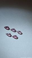 Five pink pear-cut sapphires on neutral background
