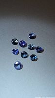 Nine round blue-violet loose gemstones on neutral background