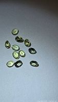 All ten yellow-green oval tanzanites on neutral background