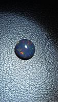 Round cabochon black opal showing red and green flashes