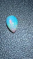 Pear cabochon opal showing blue base and multicolored pinfire