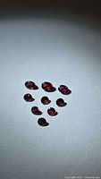 Nine loose deep red rubies arranged on white background