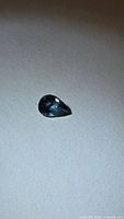 Pear-cut blue sapphire front view on neutral background