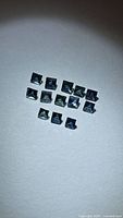 group of 14 square princess cut blue sapphires displayed on white background