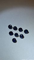 Eight round deep blue sapphires on neutral background, illuminated to show faceting