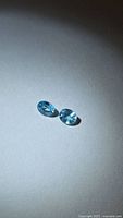 Pair of oval blue zircons on neutral background