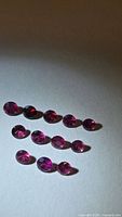 Triangular arrangement of 12 round pink-purple rhodolite garnets