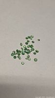 Loose green round tsavorite garnets on neutral surface