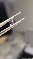 Side profile of purple spinel held by tweezers
