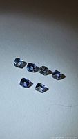 Six cushion-cut tanzanite gemstones arranged on white background