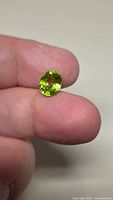 Peridot held between fingertips to illustrate size and color