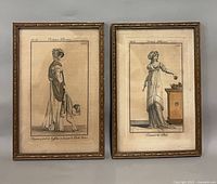 Two matching framed engravings titled "Costume Parisien" on wall
